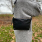 Studio pothos Cosmos bag in black with brass hardware, worn as a purse.