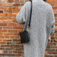 Studio pothos Cosmos bag in black with brass hardware, worn with a long strap.