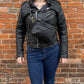 Studio pothos Cosmos bag in black with brass hardware, worn as a chest bag.